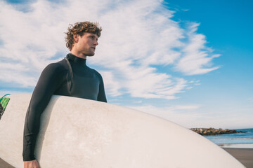 Surfer standing in the ocean with his surfboard.