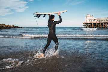 Surfer entering into the water with his surfboard.