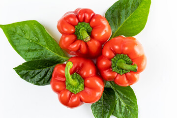 Fresh seasonal vegetables on white background. Red sweet bell pepper with green leaf. Top view. Concept of healthy nutrition.
