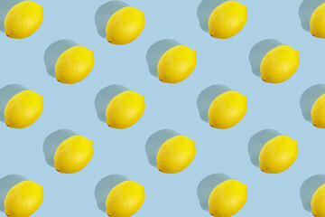 Pattern with ripe yellow lemon with a hard shadow on blue background. Minimum summer background. Concept of healthy eating.
