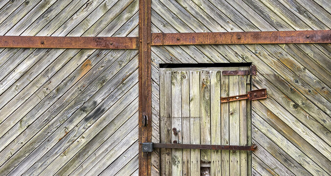 old weathered wooden gate of rural barn with closed door. panoramic view