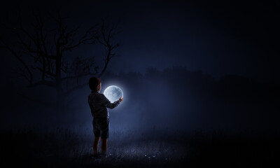 Boy holding moon at night