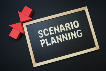 Block letters text on scenario planning on the black chalkboard and red arrows on black background