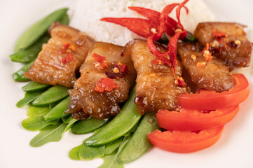 Pork belly fried on steamed rice on a plate and topped with chili paste.
