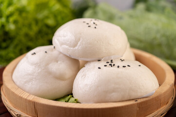 Fototapeta na wymiar Steamed buns in a wooden dish on a wooden grill.