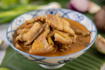 Red curry with pork belly and put morning glory in a ceramic cup.