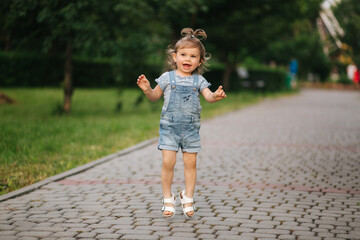 Cute little girl Eighteen month old walking in park and jump