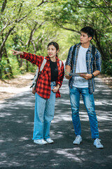 Male and female tourists look at the map on the road.