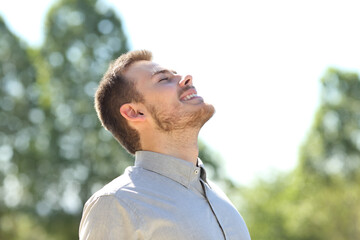 Happy man breathing fresh air standing on a park