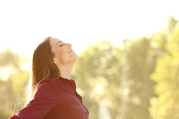 Relaxed woman breathing fresh air outdoors on a park