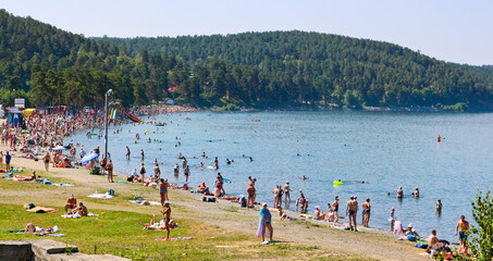 Miass, Russia - July 2020: A crowd of tourists on the shore of Lake Turgoyak. Swimming people in...