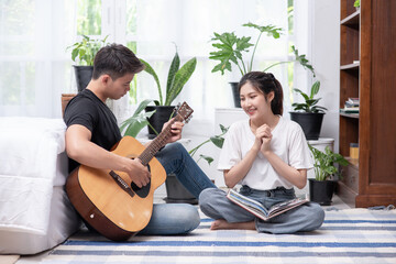 Men sitting guitar and women holding books and singing.