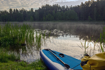 lake shore view, foreground sup board bow with yellow waterproof bag, summer