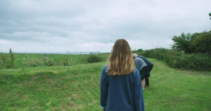 Woman walking in countryside approaching mature couple