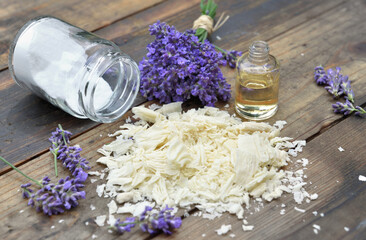 Obraz na płótnie Canvas heap of flakes of soap with essential oil and bunch of lavender flowers and sodium bicarbonate on wooden background
