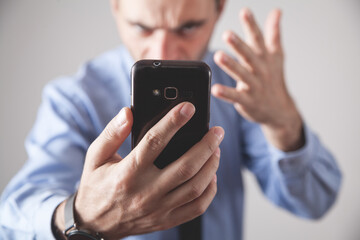 Angry caucasian businessman with smartphone.
