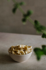 Pretty small ivory bowl with sliced banana on table in the kitchen with mint leaves decoration. Tasty and healthy vegetarian food isolated close up