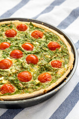 Homemade Spinach Quiche in a baking dish, side view. Close-up.