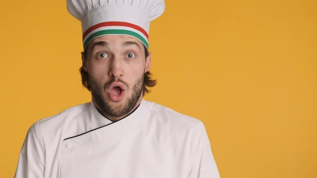 Portrait of professional excited italian chef in uniform amazedly looking in camera and showing bellissimo gesture over colorful background. wow expression. Copy space