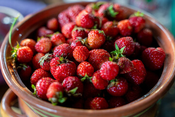 Ripe strawberries lie in an orange pot