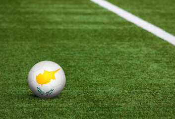 Cyprus flag on ball at soccer field background. National football theme on green grass. Sports competition concept.