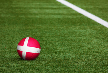Fototapeta na wymiar Denmark flag on ball at soccer field background. National football theme on green grass. Sports competition concept.