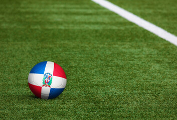 Fototapeta na wymiar Dominican Republic flag on ball at soccer field background. National football theme on green grass. Sports competition concept.
