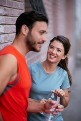 Athletic couple is having a rest after jogging in the city. Happy couple enjoying in the morning.
