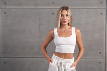 Fit and healthy blonde woman. Portrait of a sexy girl in stylish white sportswear in the studio