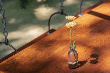 Orange daisy in glass vase on wooden table. © Apisit