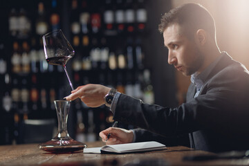 Sommeliers male tasting red wine and making notes aroma degustation card