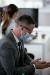 Close up of businessman disinfecting hands in the office.	
