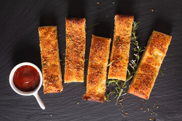 Food appetizer ideas for party concept homemade organic garlic bread stick on black slate board with copy space