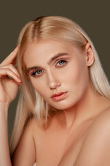 Fototapeta premium Beauty portrait. Skin rejuvenation. Blonde woman with natural makeup bare shoulders isolated on brown.