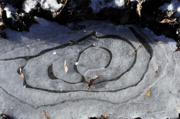 Concentric circles on the young ice of the frozen Sylva River. Clear frosty day, pre-winter in the Western Urals.