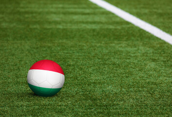 Fototapeta na wymiar Hungary flag on ball at soccer field background. National football theme on green grass. Sports competition concept.