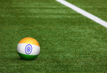 India flag on ball at soccer field background. National football theme on green grass. Sports competition concept.