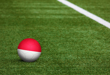 Indonesia flag on ball at soccer field background. National football theme on green grass. Sports competition concept.