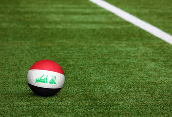 Iraq flag on ball at soccer field background. National football theme on green grass. Sports competition concept.