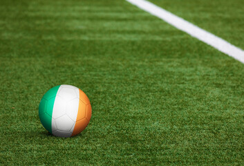 Fototapeta na wymiar Ireland flag on ball at soccer field background. National football theme on green grass. Sports competition concept.