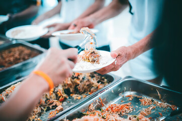 Hands of volunteers serves free food to the poor