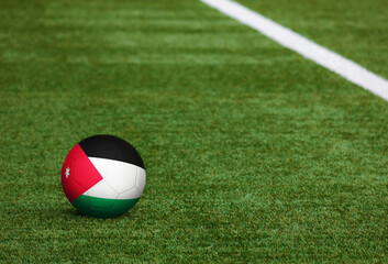 Fototapeta na wymiar Jordan flag on ball at soccer field background. National football theme on green grass. Sports competition concept.