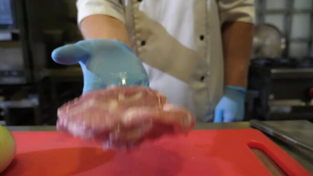 Cook throwing a slab of raw meat tenderiser on a kitchen table in slow motion