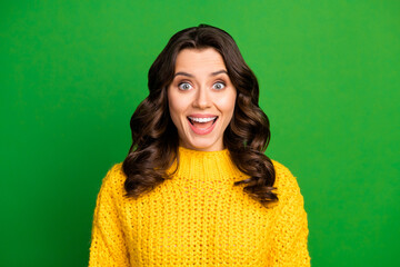 Photo of pretty funny curly lady positive cheerful mood open mouth listen cool news excited wear yellow casual knitted sweater isolated green bright color background