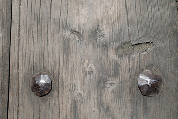 Heads of nails driven into the ground of a wooden medieval bridge