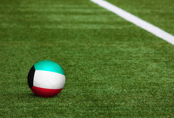 Fototapeta na wymiar Kuwait flag on ball at soccer field background. National football theme on green grass. Sports competition concept.
