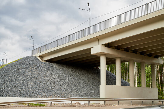Bottom view of the prestressed concrete beams and piers of bridge crossing many-lane expressway of road.