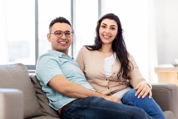 love, relationships and people concept - happy couple sitting on sofa at home