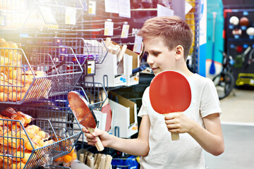 Boy with rackets for table tennis in sport store