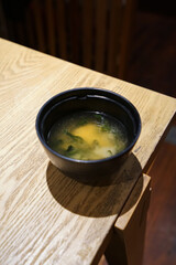 Close up bowl of Miso soup on wooden table, traditional Japanese soup consisting of a stock called 